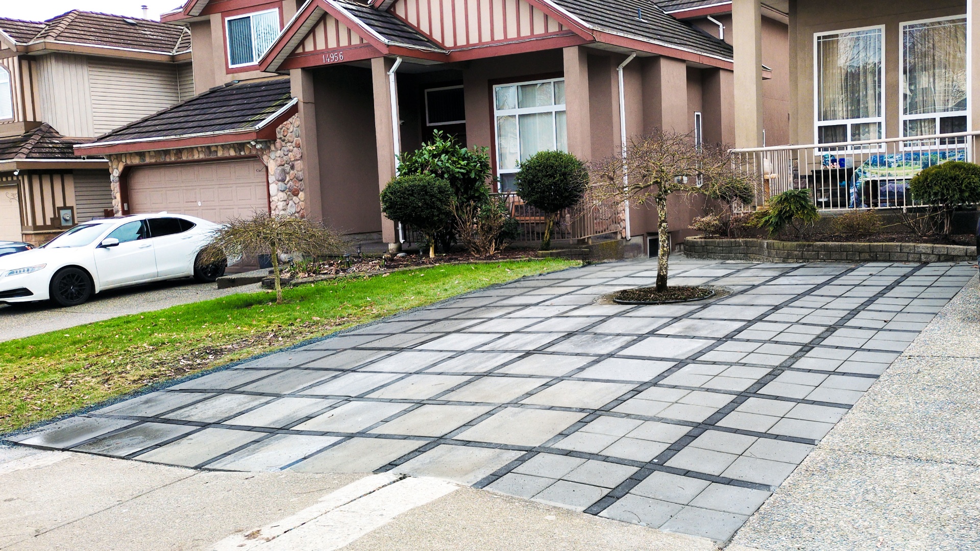 Finished slab driveway with charcoal grid bands and tree well