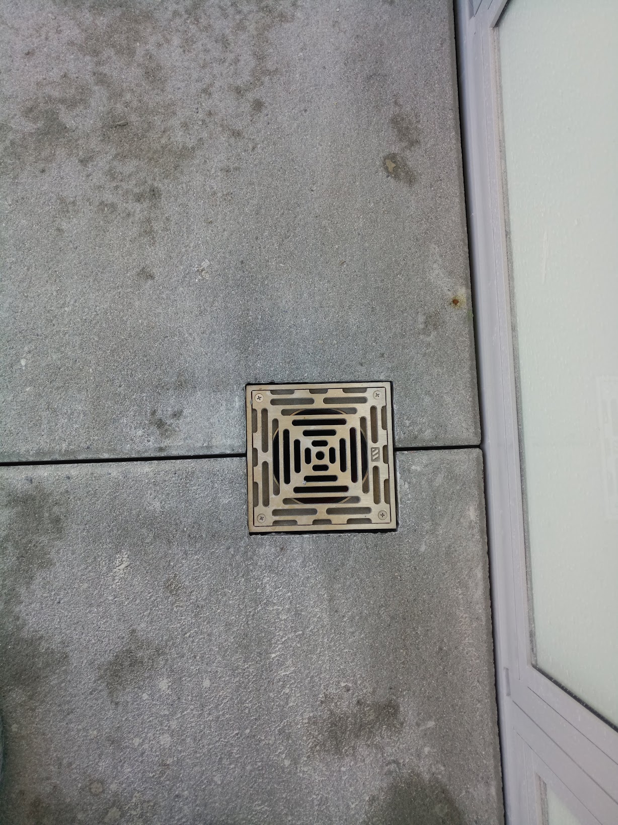 Recessed bronze drain grate set flush between two granite pavers