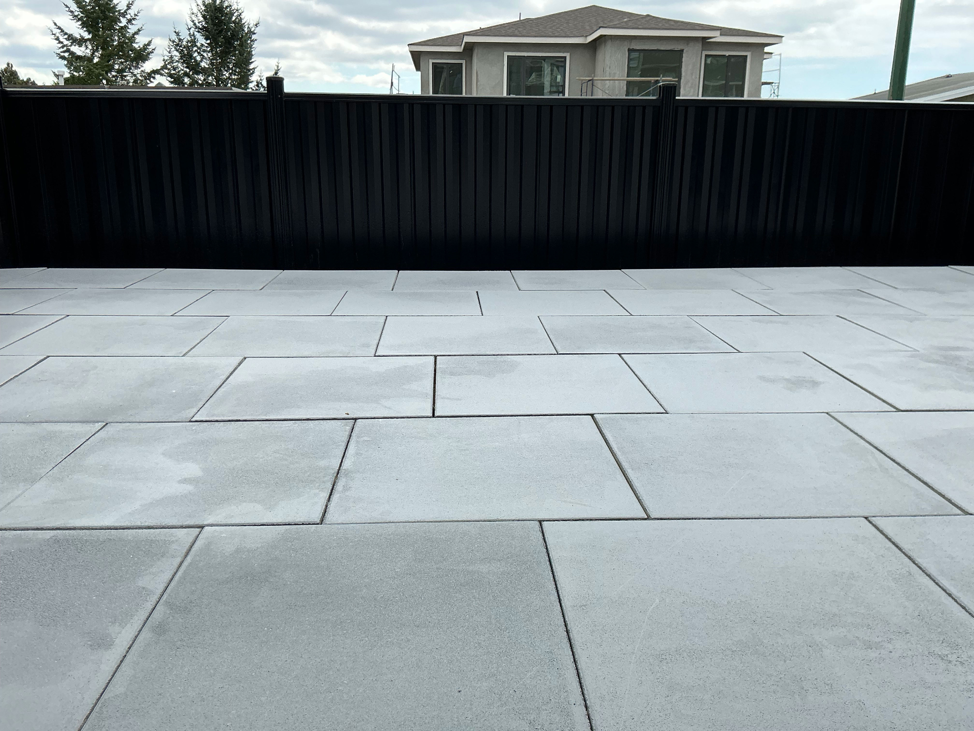 Coquitlam — wide finished slab patio looking across the property to the home behind