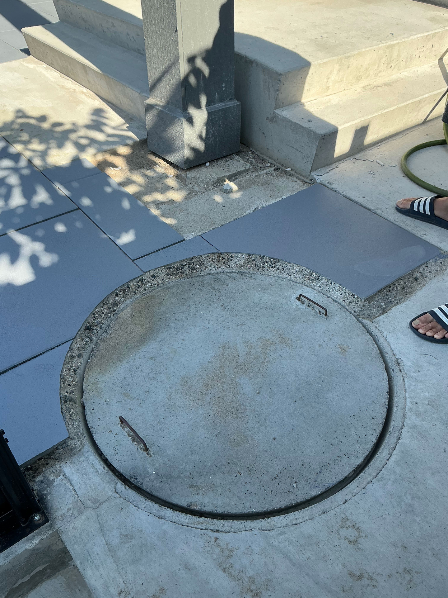 Custom slab cuts wrapping a circular manhole at the foot of the entry steps