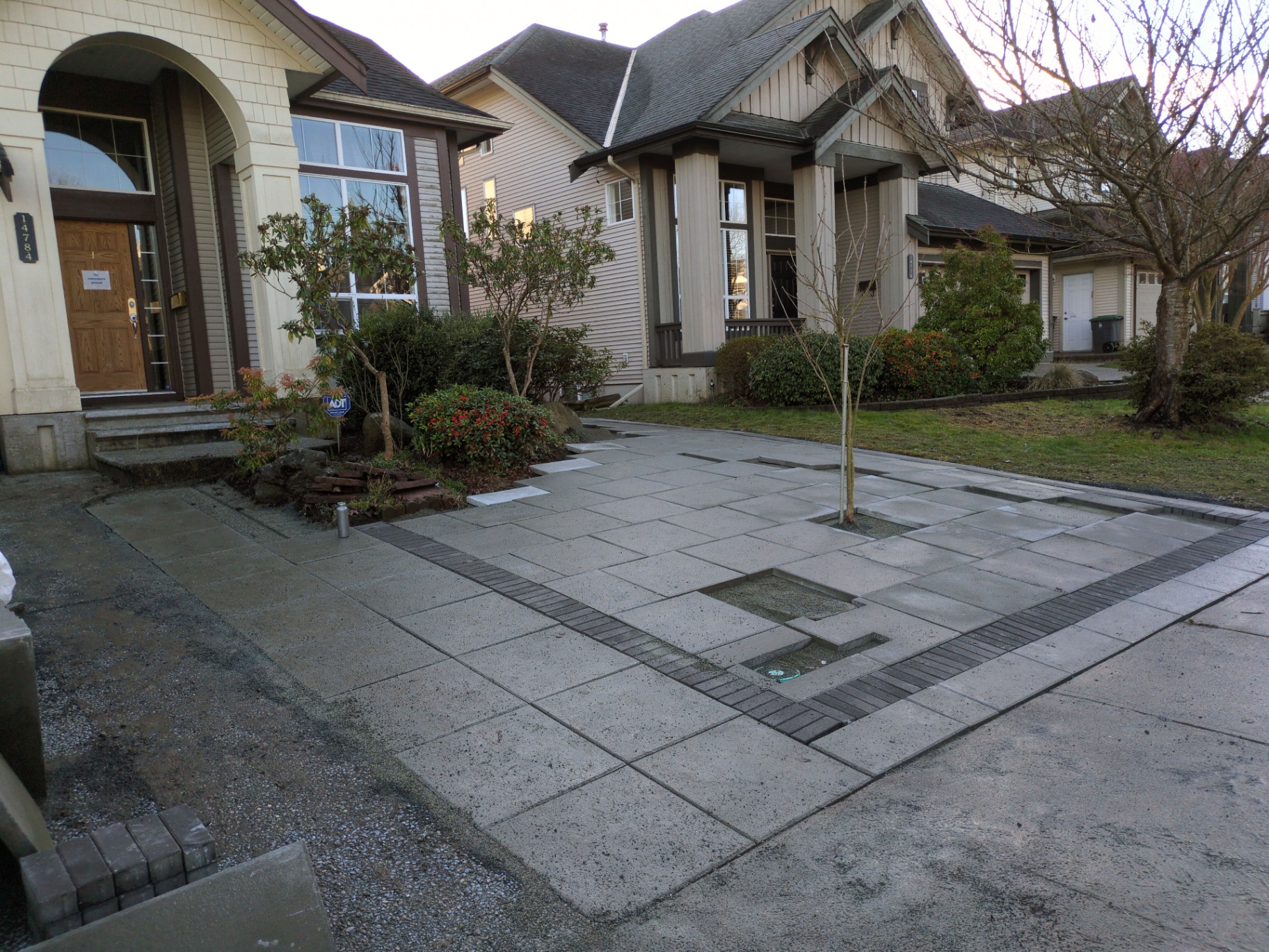 Driveway nearing completion with charcoal border, tree well, and full slab field installed