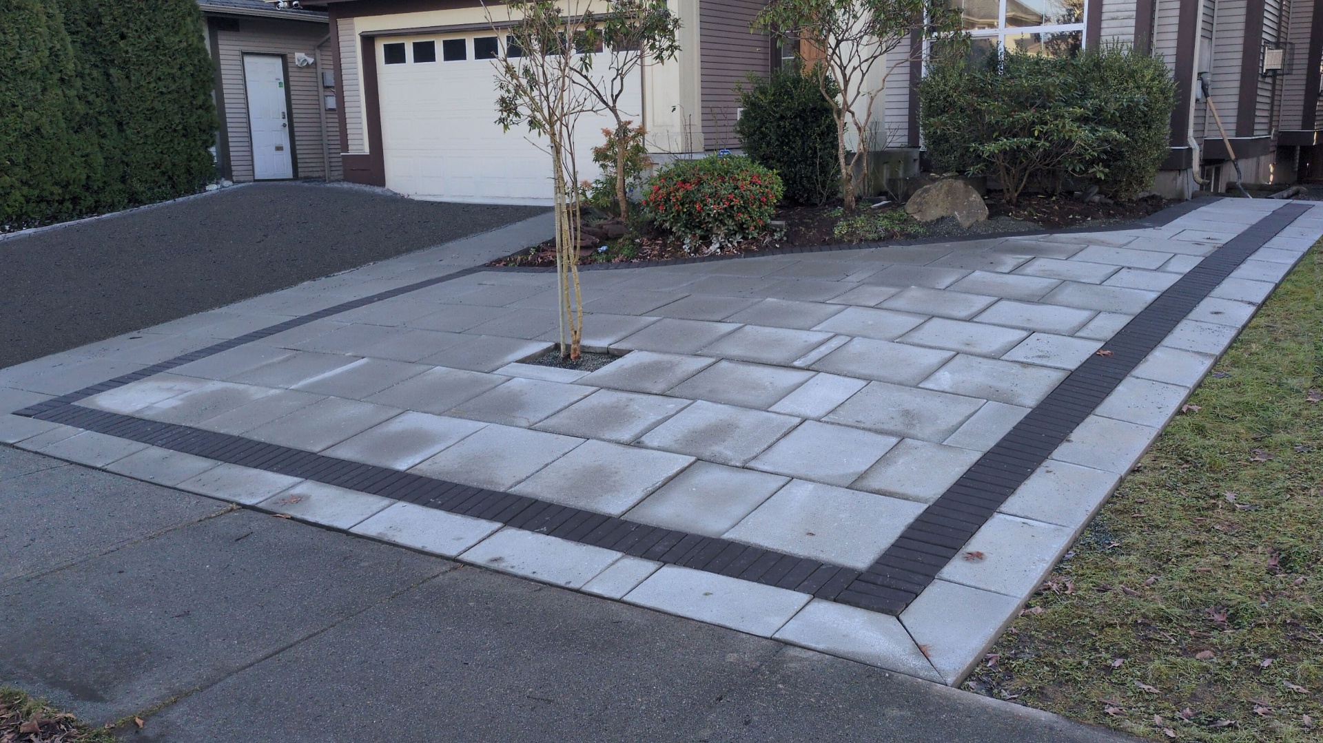 Wide angle of the finished slab driveway showing charcoal banding wrapping the perimeter