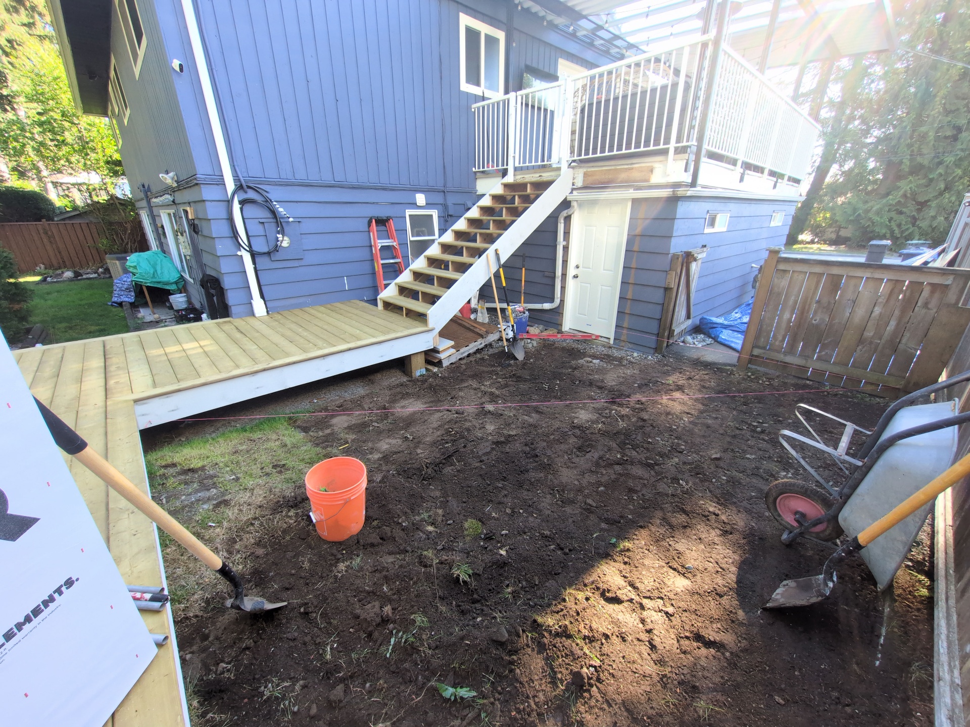 Backyard prepped with fresh dirt grade beneath the elevated deck and stair landing