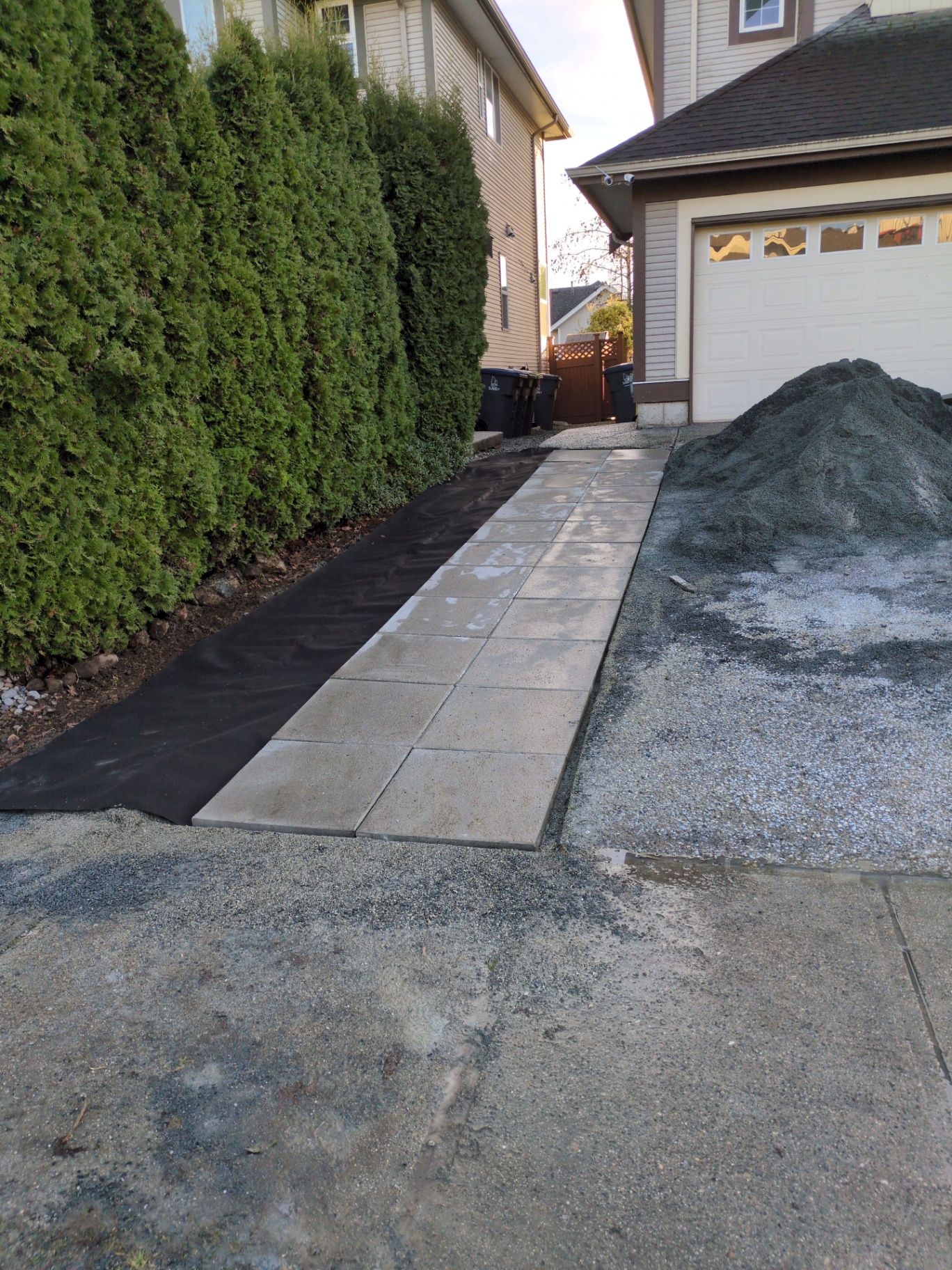 Pavers being set on landscape fabric beside a fresh pile of bedding sand
